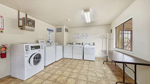 A laundry room with a row of washers and dryers.