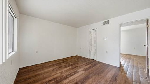 A room with wooden flooring and white walls.