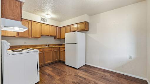 A kitchen with white appliances and wooden cabinets.