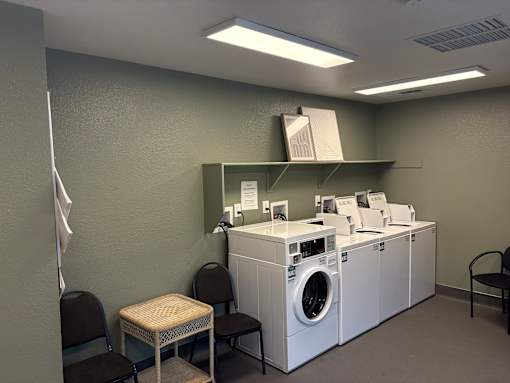 A laundry room with a washer and dryer, a table, and chairs.