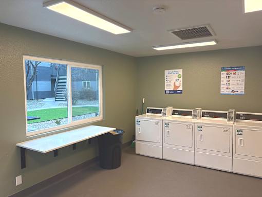 A laundromat with washers and dryers and a bench.
