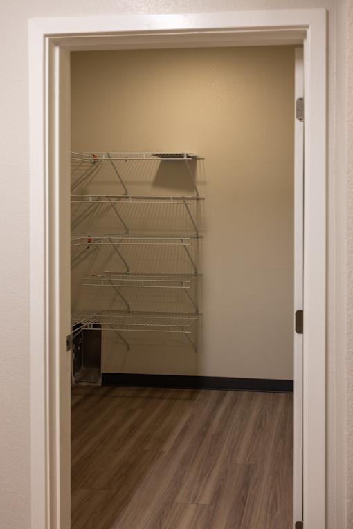 a room with a white door and a mirrored closet with shelves