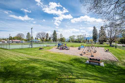 a playground with swings and a picnic table in a park