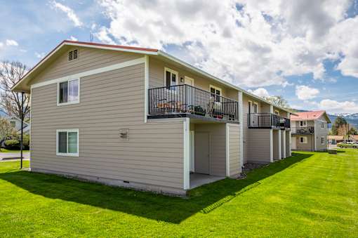 the view of an apartment building with a green lawn