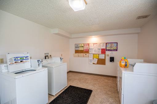 a laundry room with washes and dryers and a bulletin board on the wall