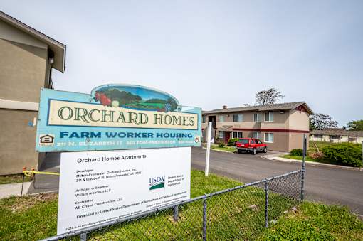 a sign that reads orchard homes farm worker housing with a building in the background