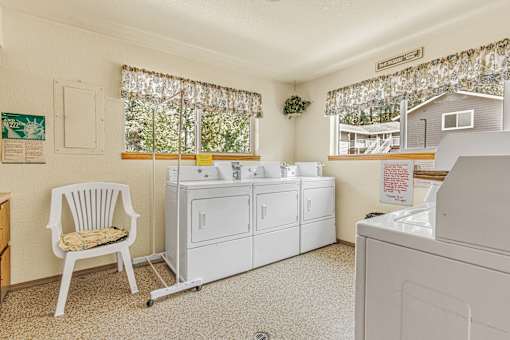 a laundry room with white appliances and a white chair