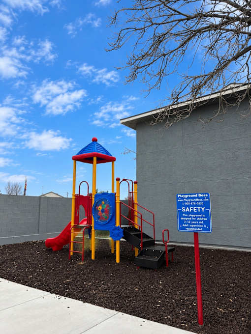 A playground with a slide and a safety sign.