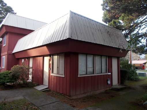 A red house with a grey roof and a white door.
