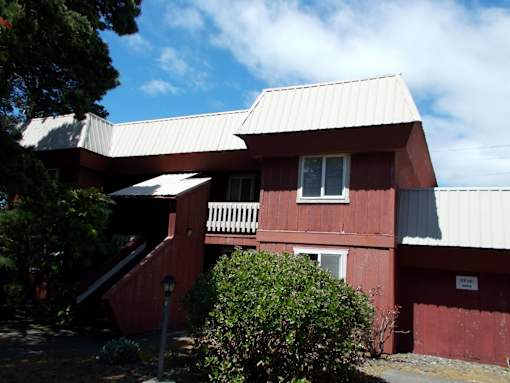 A red building with a white roof and a sign on the side.