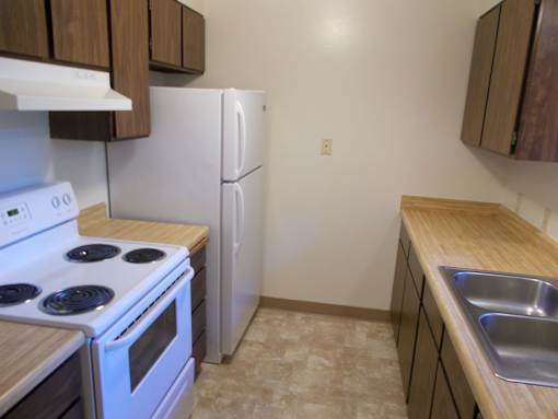 A kitchen with a white stove, white refrigerator, and wooden cabinets.