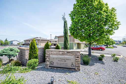 The sign in front of the building says "The Greens at Spring Apartments".