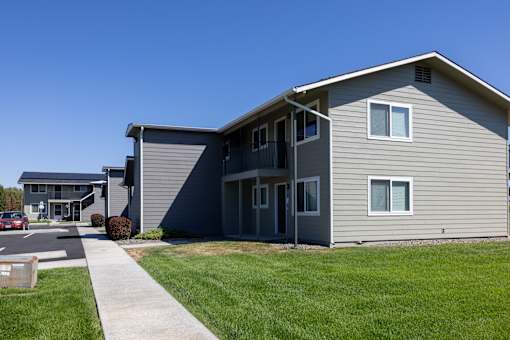 an apartment building with gray siding and a sidewalk