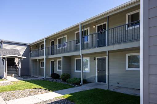 an exterior view of an apartment building with a sidewalk and grass