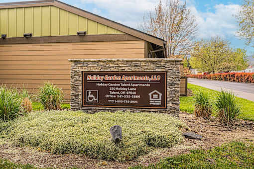 A sign for Holiday Garden Apartments, LLC is displayed in front of a building.
