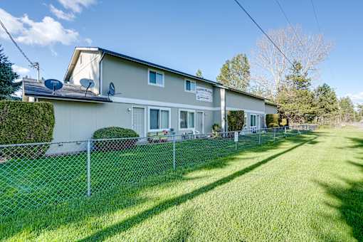 A house with a fence and green lawn in front.
