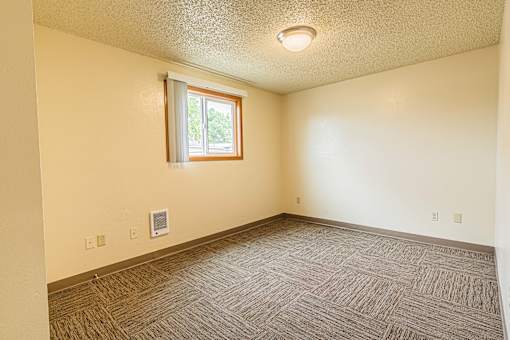 A room with a window and a carpeted floor.
