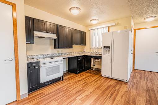 A kitchen with black cabinets and white appliances.
