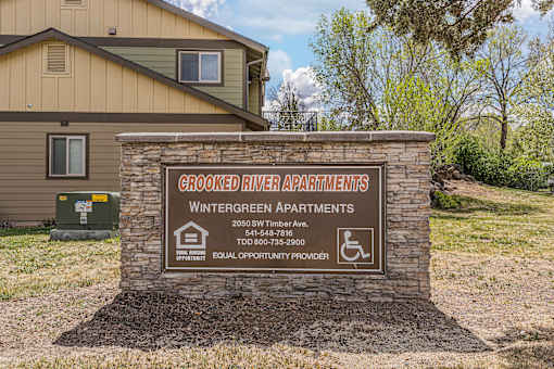 A sign for the Wintergreen Apartments stands in front of a building.