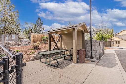 A picnic table is located under a shelter in a park.