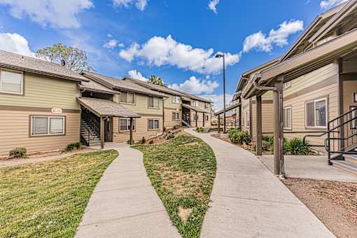 A row of houses with a sidewalk in front.