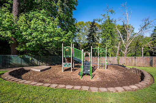 A playground with a green swing set and a sign that says "Kids Play Area".