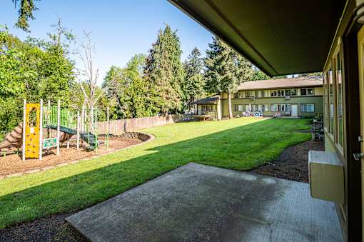 A playground with a slide and a green lawn.