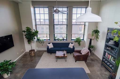 A living room with a blue couch and a large window.