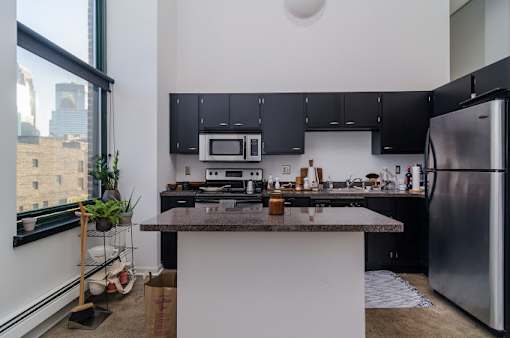 A kitchen with a black counter top and stainless steel appliances.