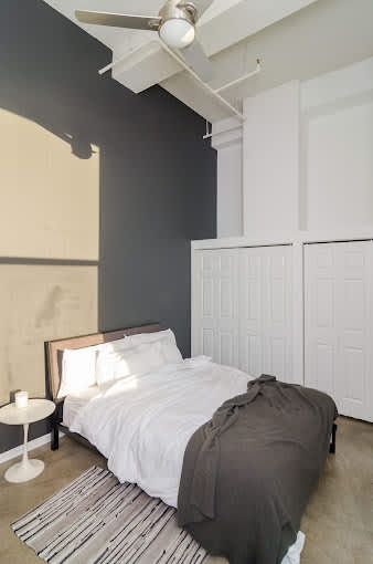A bedroom with a bed, a nightstand, and a ceiling fan.