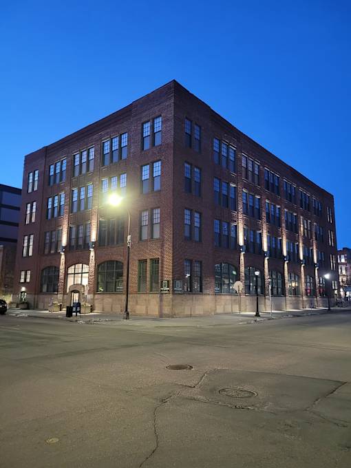 A large red brick building with many windows is lit up by a street lamp.