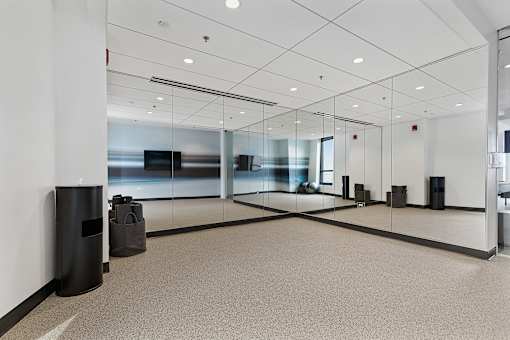 A hallway with a glass wall and a trash can.