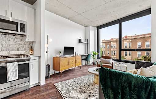 an open living room with a kitchen and a large window