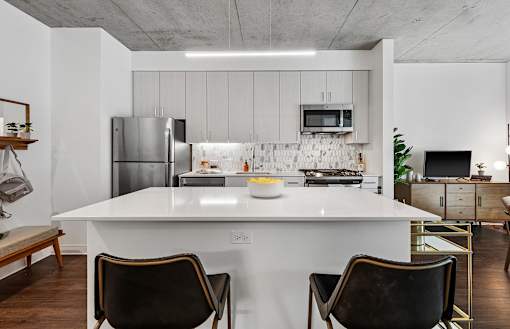 a kitchen with a white island and a stainless steel refrigerator