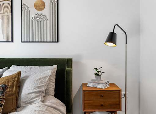 a bedroom with a bed and a night stand with a lamp