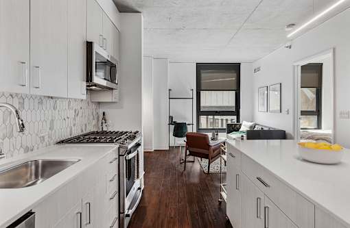 a kitchen and living room with white cabinets and a sink