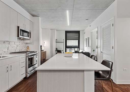an open kitchen with a large white island and a dining table