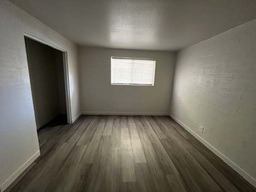 A room with a window and wooden flooring.