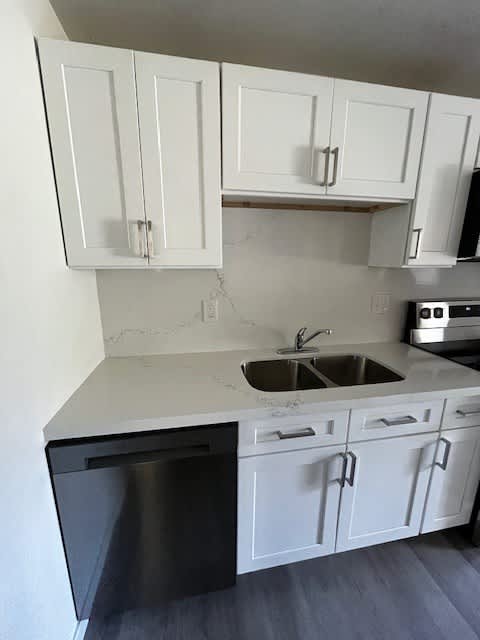 A kitchen with white cabinets and a black dishwasher.