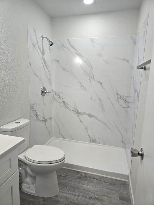 A white toilet in a bathroom with marble wallpaper.