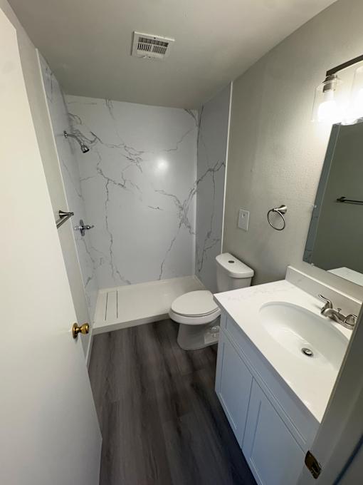 A bathroom with a marble shower and toilet.