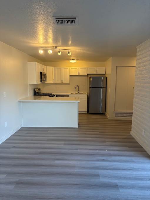 A kitchen with a refrigerator, microwave, and oven.