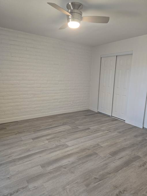A room with a ceiling fan and a wooden floor.