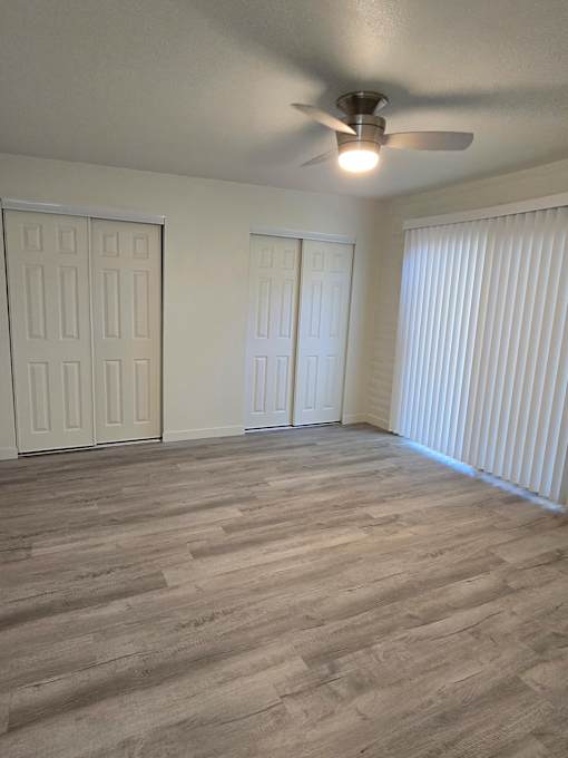 A room with a ceiling fan and two doors.