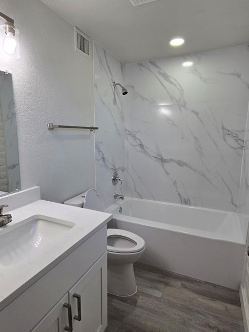 A white bathroom with a marble wall and a toilet.