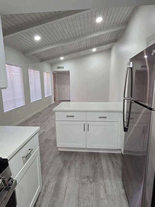 A kitchen with white cabinets and a stainless steel refrigerator.