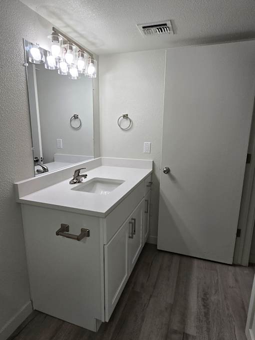 A white bathroom with a sink and mirror.