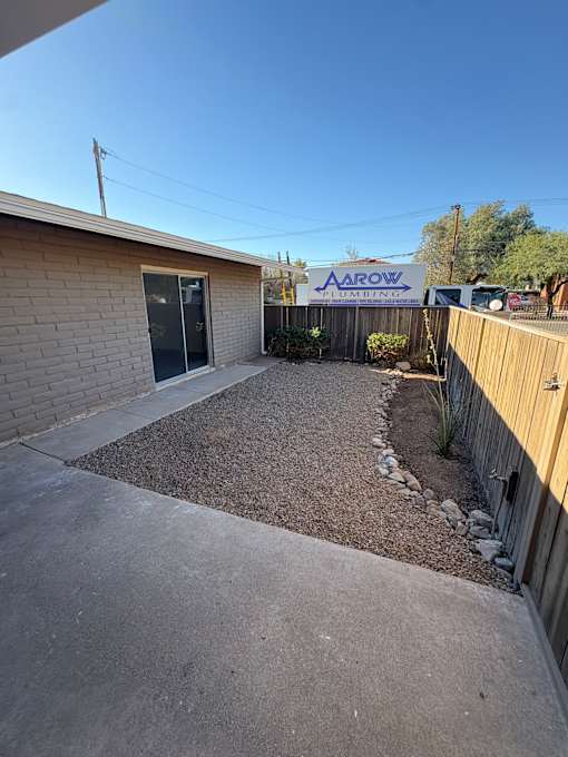 A small backyard with a gravel area and a wooden fence.