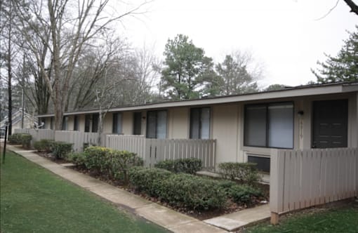 A long building with a fence and bushes in front.