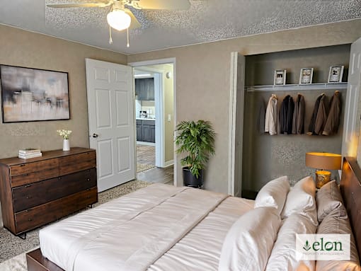 A bedroom with a bed, dresser, and coat rack.